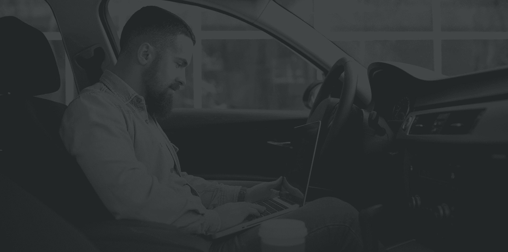 Persona in auto che consulta il portatile