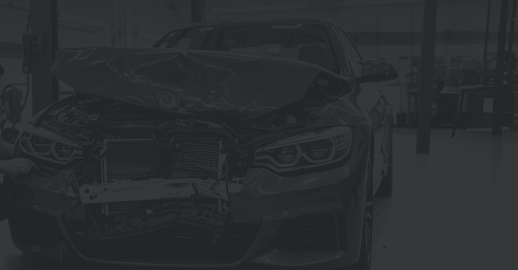 Front view of a severely damaged BMW inside an auto repair workshop